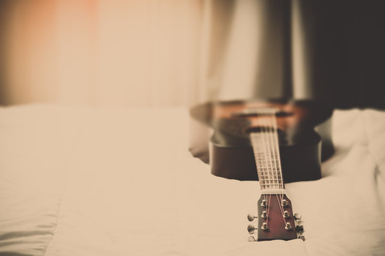 acoustic guitar on bed in the morning, vintage filter.