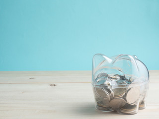 transparent see through piggy bank filled with coins on wood background.Saving investment colorful concept.