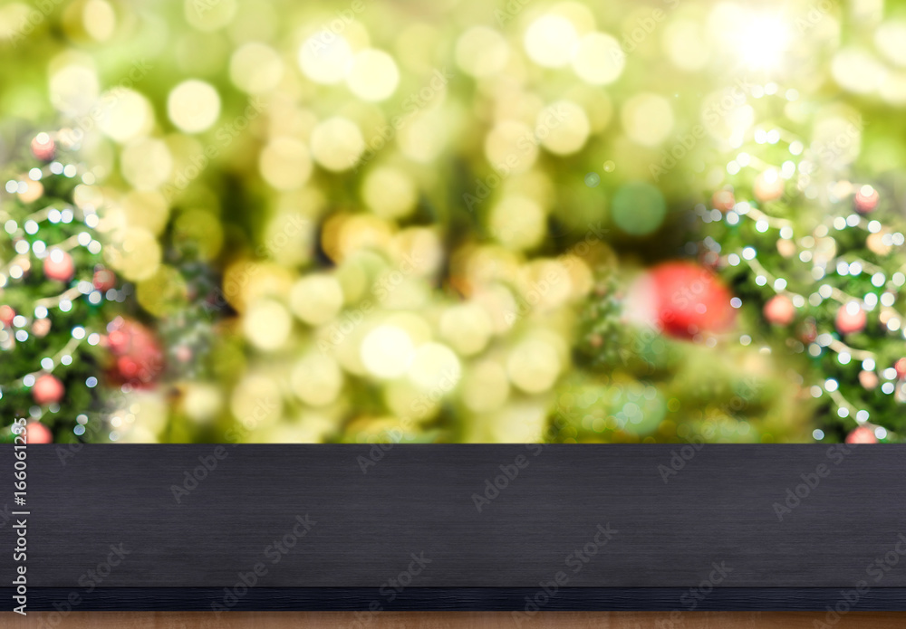 Poster Black wooden table top with abstract blur christmas tree background with bokeh light,Holiday backdrop,Mock up for display or montage of product.