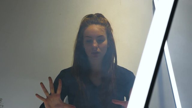 A young woman reaches out to grab at the air. Filmed from medium close up.