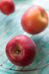 Red apples on a turquoise background. Vertical orientation. Selective focus.
