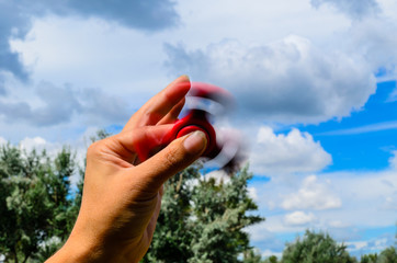 Red fidget spinner rotates in female hand