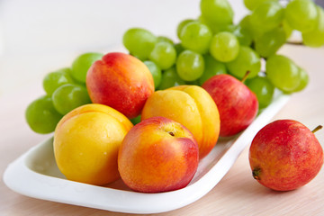 Peaches and grapes on a white plate