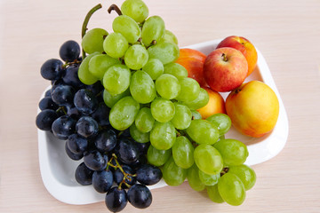 A bunch of white and black grapes on a white plate