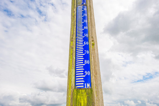 Ancient tide gauge pointing into a blue cloudy sky