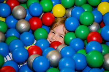 Fototapeta na wymiar Девочка в бассейне с разноцветными шариками