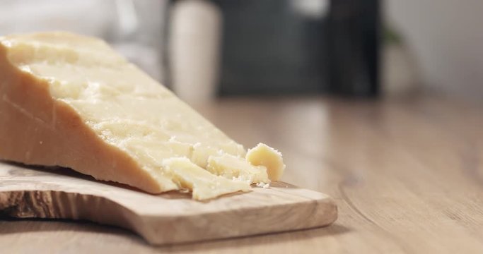 Slow motion slide of female hand taking pieces of hard parmesan cheese from olive board