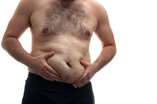 Obesity epidemic awareness and unhealthy eating habits concept with an overweight man with a hairy chest pinching the fat underneath the belly, isolated on white background with clipping path