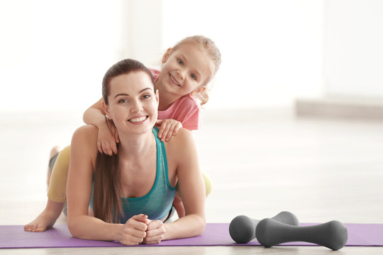 Mother and daughter in gym on light background