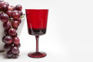 Bunch of ripe grapes with red glass