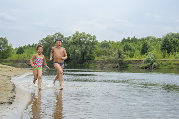 Fototapeta na wymiar In summer, children run along the river bank.