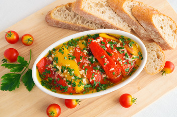 red and yellow marinated bell peppers in serving dish, garnished with bread and decorated with...