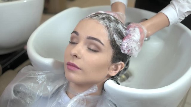 Beautician washing head of client. Hair covered in shampoo foam. Best natural shampoo.
