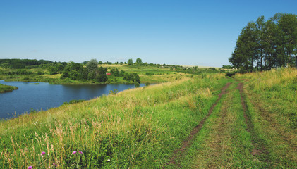 Fototapeta na wymiar Sunny summer scene.Landscape with ground countryside road and flowing river Krasivaya in Tula region,Russia