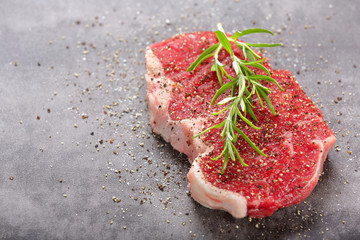 Fresh raw beef steak on stone board with spices