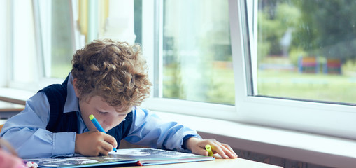 Boy does the lesson exercise during the lesson of primary school.