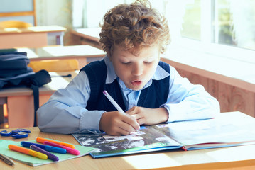 Little child writing with colorful pencils, indoors. Elementary school and education. Kid learning writing letters and numbers.