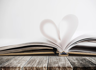 Heart shape in opened notebook page, on wooden table