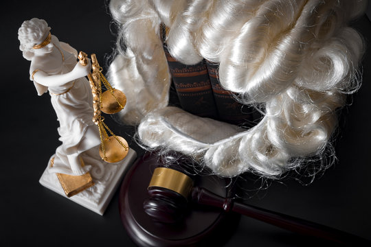 Legal code, enforcement of the law and blind Iustitia concept with statue of the blindfolded lady justice ( Dike in Greek and Justitia in Roman mythology), books, a white powdered wig and a gavel