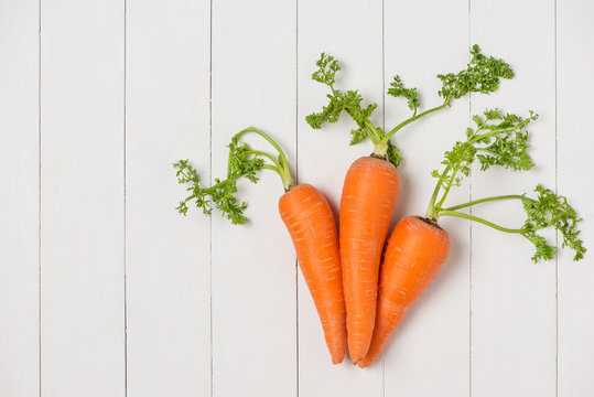 Fresh organic carrots on white wooden background