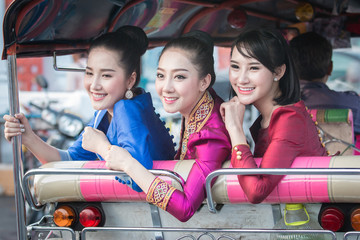 Beautiful Thai Girl in Thai Dress Traveling by Tuk Tuk in Bangkok,Are very happy.
