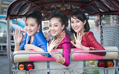 Naklejka premium Beautiful Thai Girl in Thai Dress Traveling by Tuk Tuk in Bangkok,Are very happy.