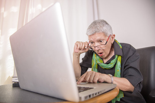 Senior business woman shocked with the content she finds on her laptop