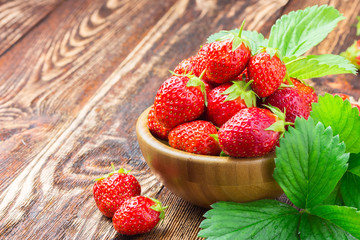 Fresh strawberry in a bowl on rustic wooden background. Top view copy space.  