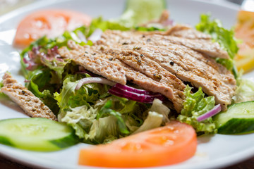 Steak with tomatoes, cucumbers and herbs on a white plate