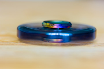 ein exklusiver Fidget Spinner aus Metall dreht sich schnell und liegt auf Holz