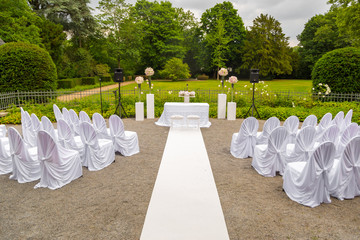 Scenery of the wedding ceremony in the park. White frame decorated with flowers. Ceremony in white style