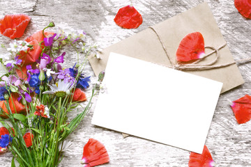 blank white greeting card with wildflowers bouquet and envelope with flower petals