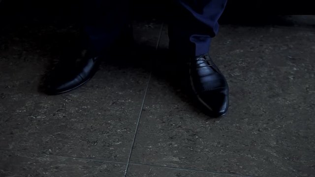 Man tying patent leather shoes.