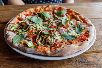 Vegetarian pizza on a white plate in a restaurant