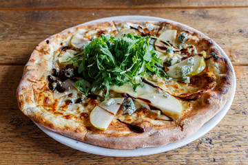 Four cheese pizza on a white plate with rucola lettuce