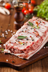 Raw pork ribs, on a plate sprinkled with spices.