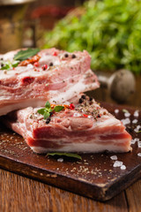 Raw pork ribs, on a plate sprinkled with spices.