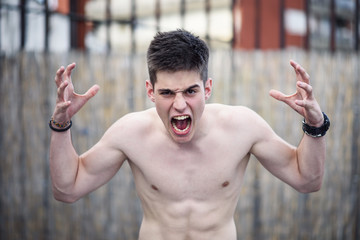 Young frustrated shirtless man screaming with rage and frustration