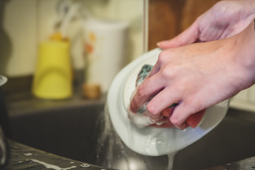 Young woman washing dishes closeup