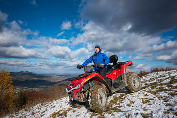 Man on atv riding down from the snow-capped peaks on a sunny day. Beautiful mountain landscape...