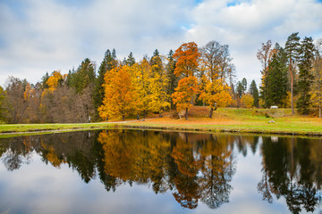 Red and orange autumn foliage reflected in the clear water of the pond.