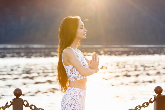 Portrait of beautiful young woman doing yoga in nature in summer sunrise. Relaxing, meditating, feeling alive, breathing, freedom and calm concept, copy space