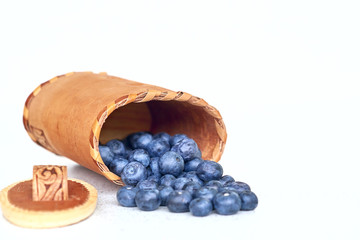 Blueberries near bark basket on a white background