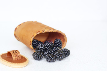 Blackberries near bark basket on a white background