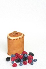 Blueberries, raspberries and blackberries near bark basket on a white background 2