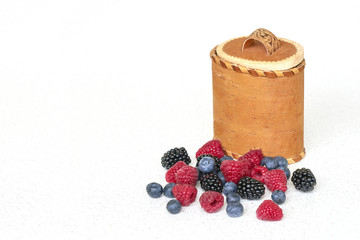 Blueberries, raspberries and blackberries near birch bark basket 