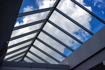 view of the cloudy sky through the glass roof