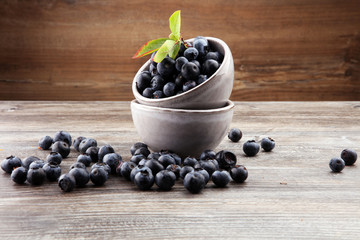 Freshly picked blueberries in wooden bowl. Juicy and fresh blueberries with green leaves on rustic table. Bilberry on wooden Background. Blueberry antioxidant. Concept for healthy eating and nutrition