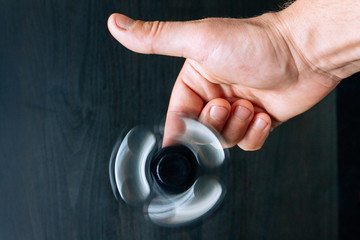 A hand with rolling spinner with black wooden background