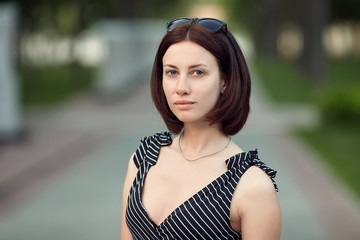 Lifestyle portrait adult adorable fresh looking brunette woman with no make up bob hairdo posing evening park showing emotion and facial expression concept.